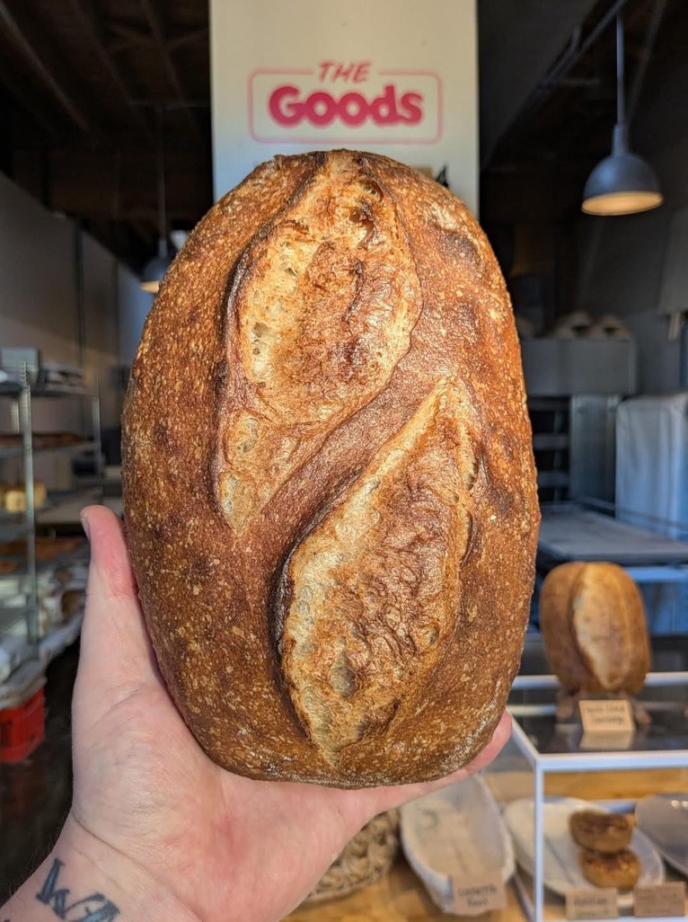Sourdough loaf held in front of the Good Dough counter